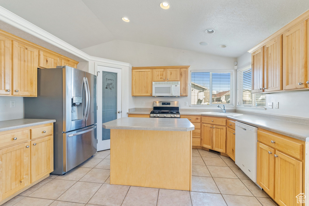 Kitchen with appliances with stainless steel finishes, light tile floors, a kitchen island, sink, and vaulted ceiling