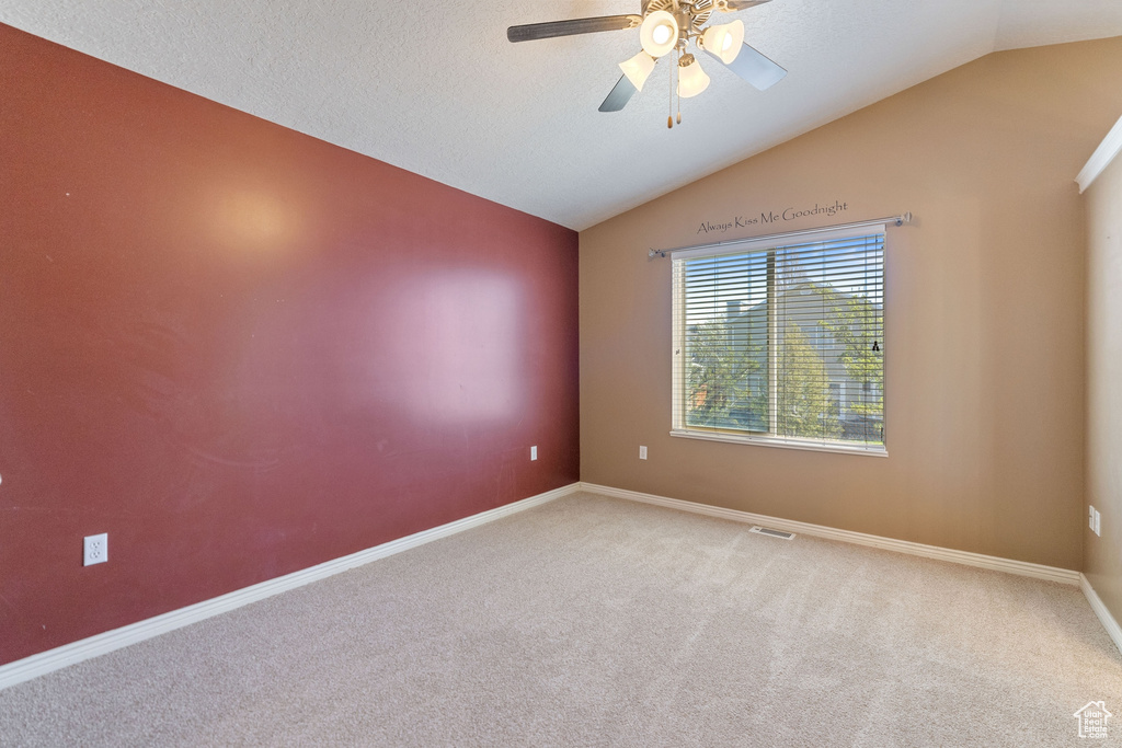 Carpeted empty room with lofted ceiling and ceiling fan