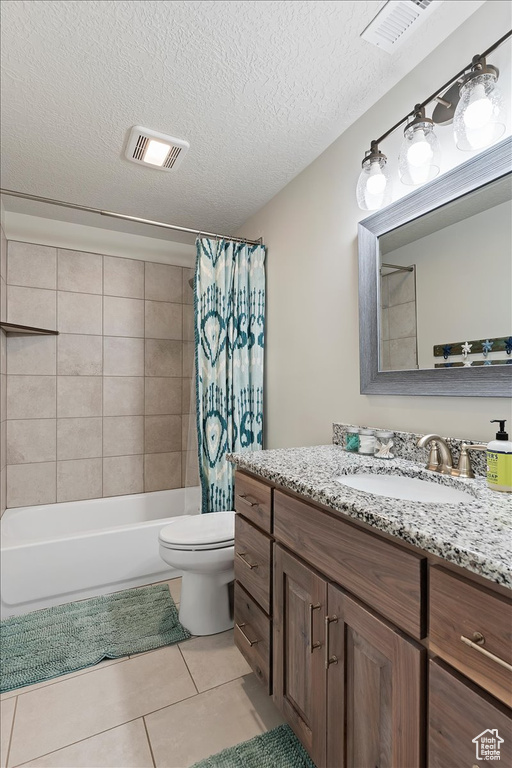 Full bathroom featuring toilet, shower / bath combo with shower curtain, tile flooring, a textured ceiling, and vanity