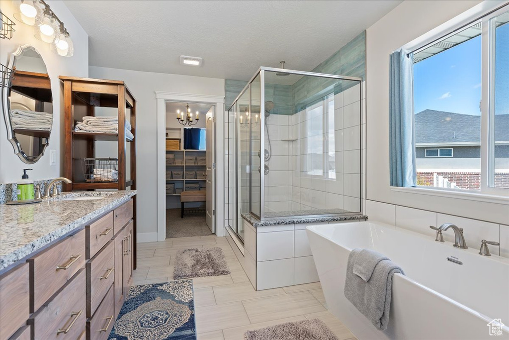 Bathroom with tile floors, a chandelier, oversized vanity, and shower with separate bathtub