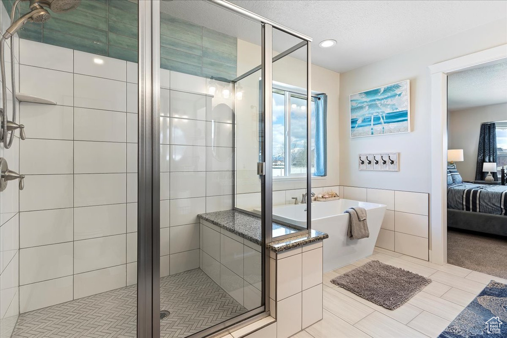Bathroom featuring a textured ceiling, tile walls, plus walk in shower, and tile floors