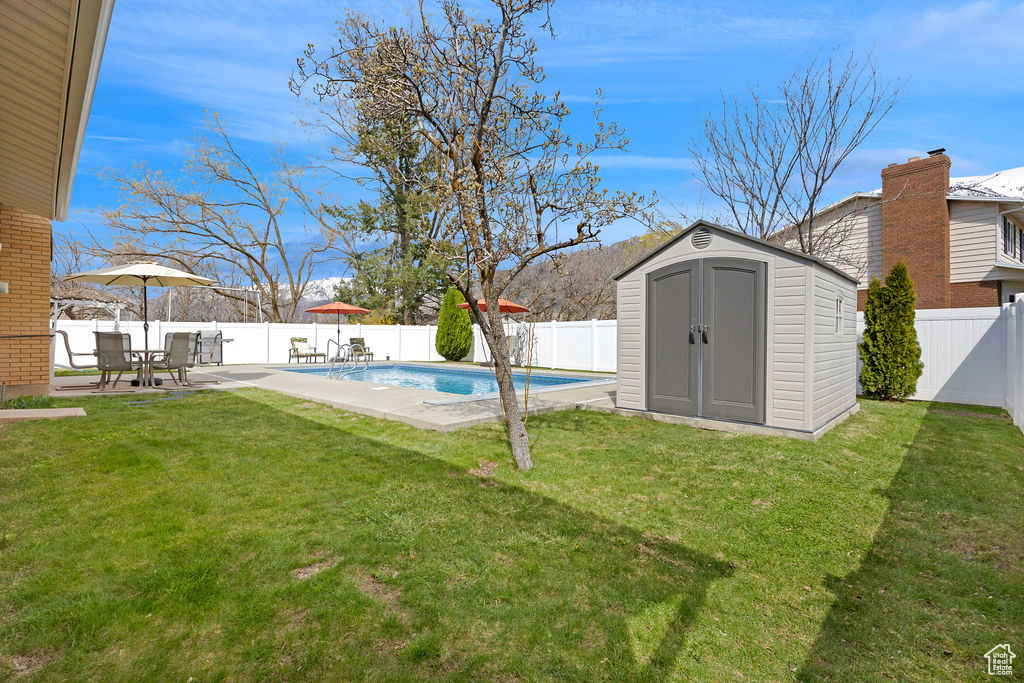 View of yard featuring a storage unit, a patio area, and a fenced in pool