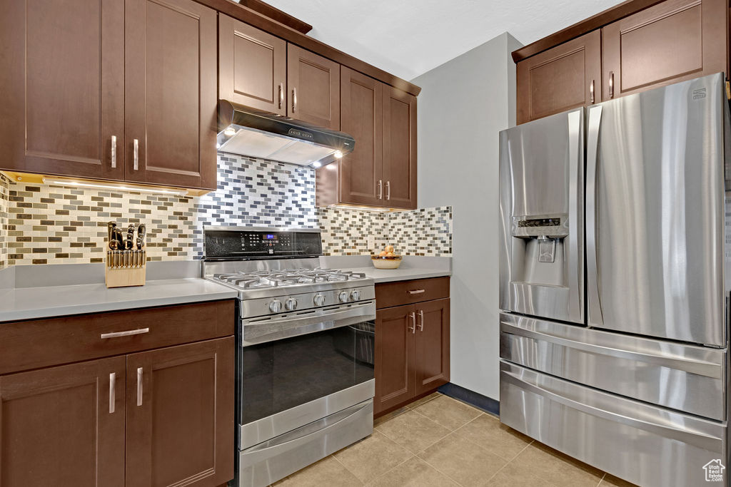 Kitchen with appliances with stainless steel finishes, backsplash, and light tile flooring