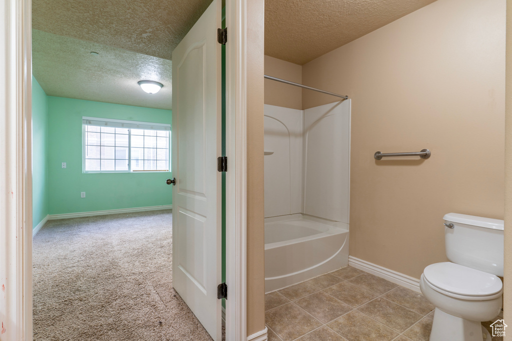 Bathroom featuring tile flooring, a textured ceiling, toilet, and tub / shower combination