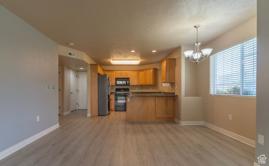Kitchen featuring pendant lighting, stainless steel fridge, light hardwood / wood-style floors, and stove