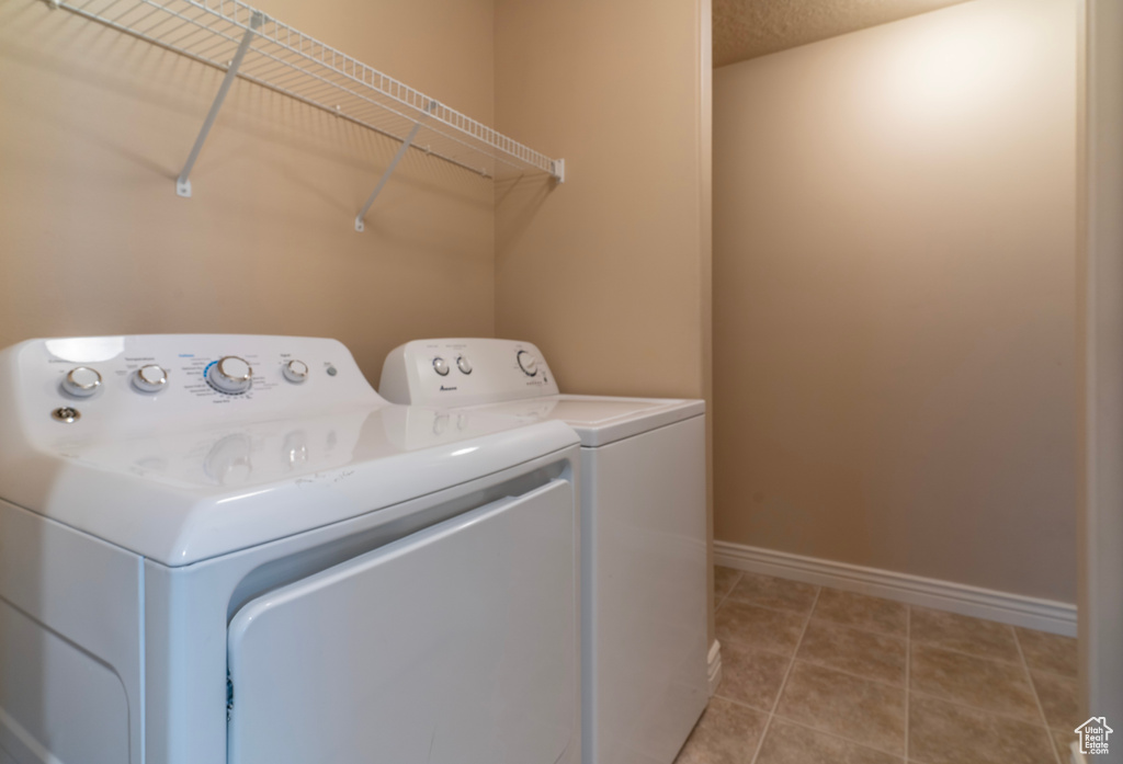 Laundry room featuring washing machine and dryer and light tile flooring