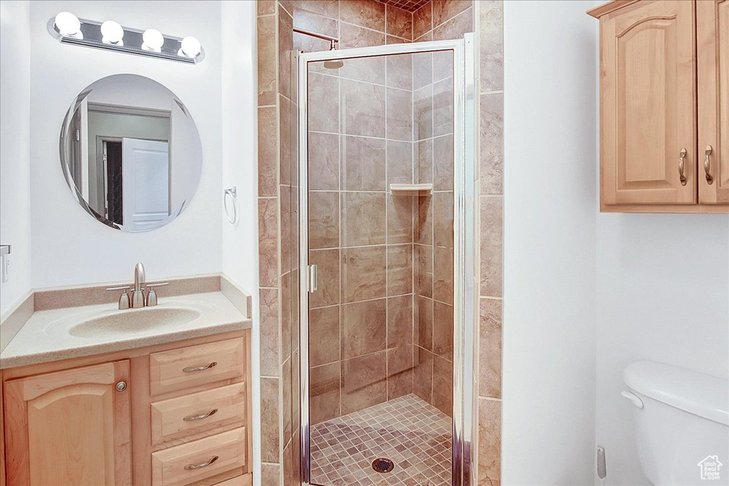Bathroom with toilet, vanity, and an enclosed shower
