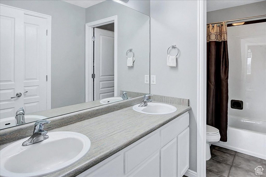 Full bathroom with shower / bathtub combination with curtain, tile floors, large vanity, dual sinks, and toilet