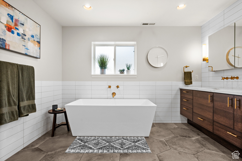 Bathroom with tile walls, tile flooring, and vanity