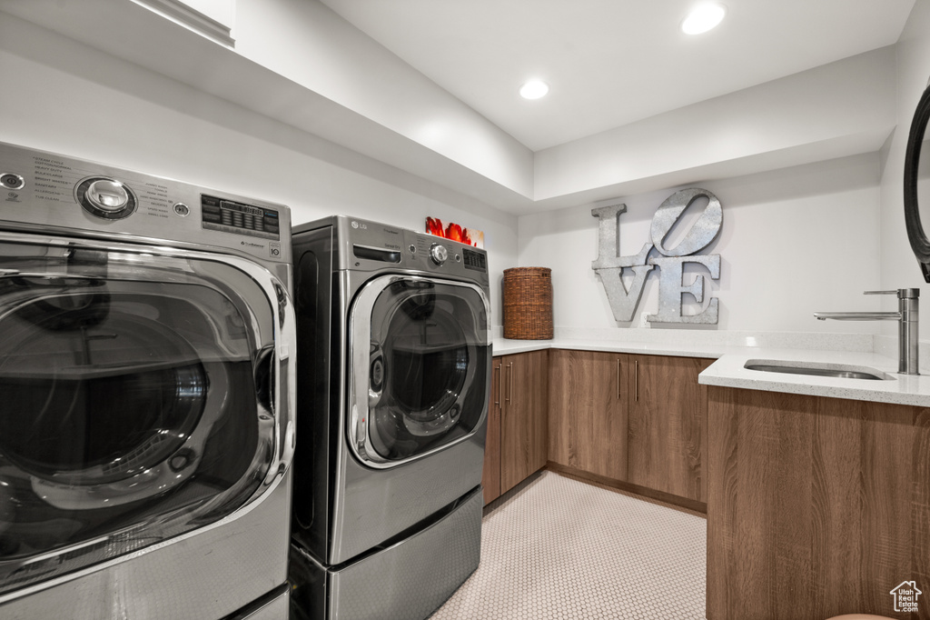 Laundry room featuring light tile flooring, independent washer and dryer, and sink