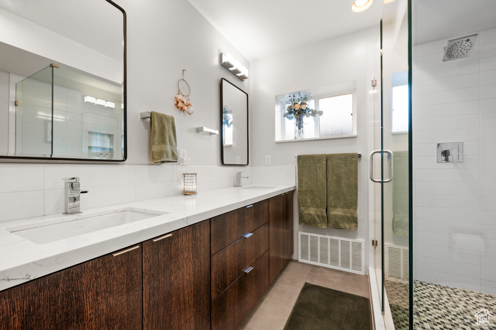 Bathroom with a shower with door, tile floors, tasteful backsplash, and double vanity