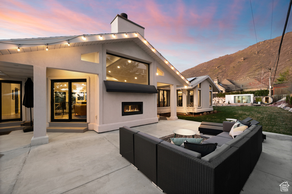 Patio terrace at dusk with a lawn, outdoor lounge area, and a mountain view
