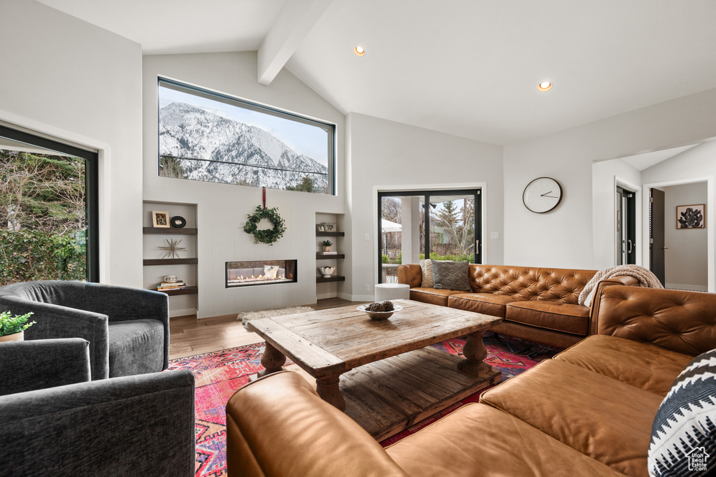 Living room with a mountain view, high vaulted ceiling, beam ceiling, and wood-type flooring