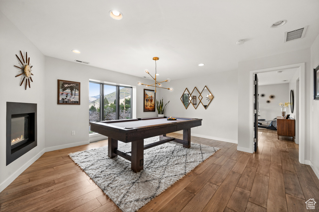Rec room with pool table, light hardwood / wood-style floors, and an inviting chandelier