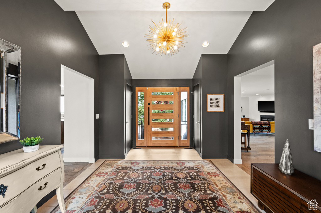 Tiled foyer with lofted ceiling and a notable chandelier