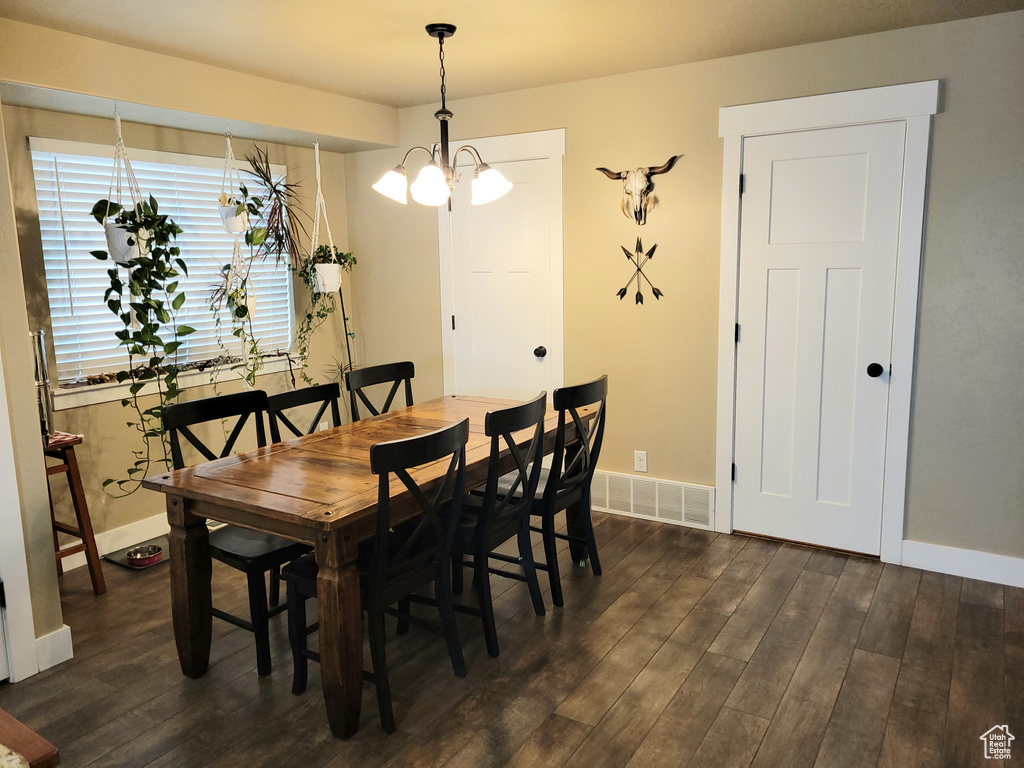 Dining room with dark hardwood / wood-style flooring and a chandelier