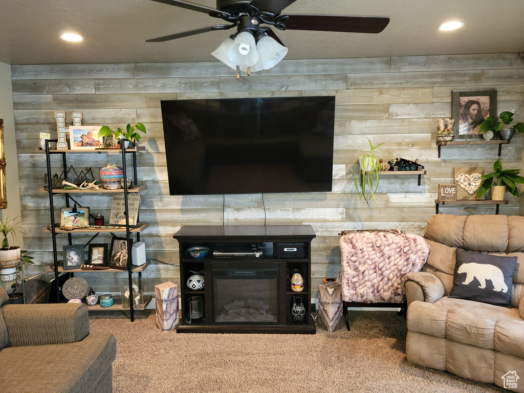 Carpeted living room with wooden walls and ceiling fan