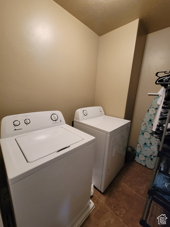 Clothes washing area featuring washing machine and clothes dryer and dark tile flooring