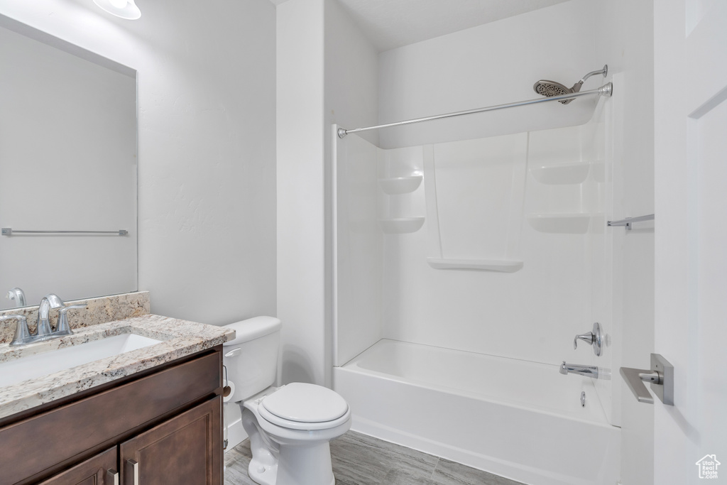 Full bathroom with toilet, bathtub / shower combination, hardwood / wood-style flooring, and vanity
