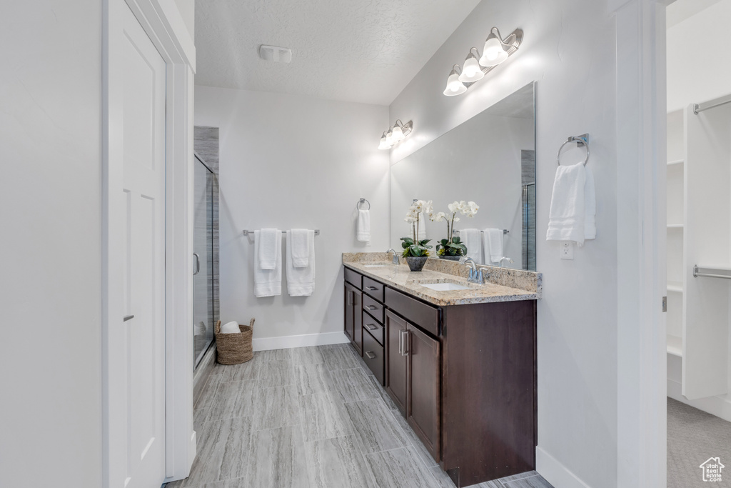 Bathroom with tile floors, double vanity, and a textured ceiling