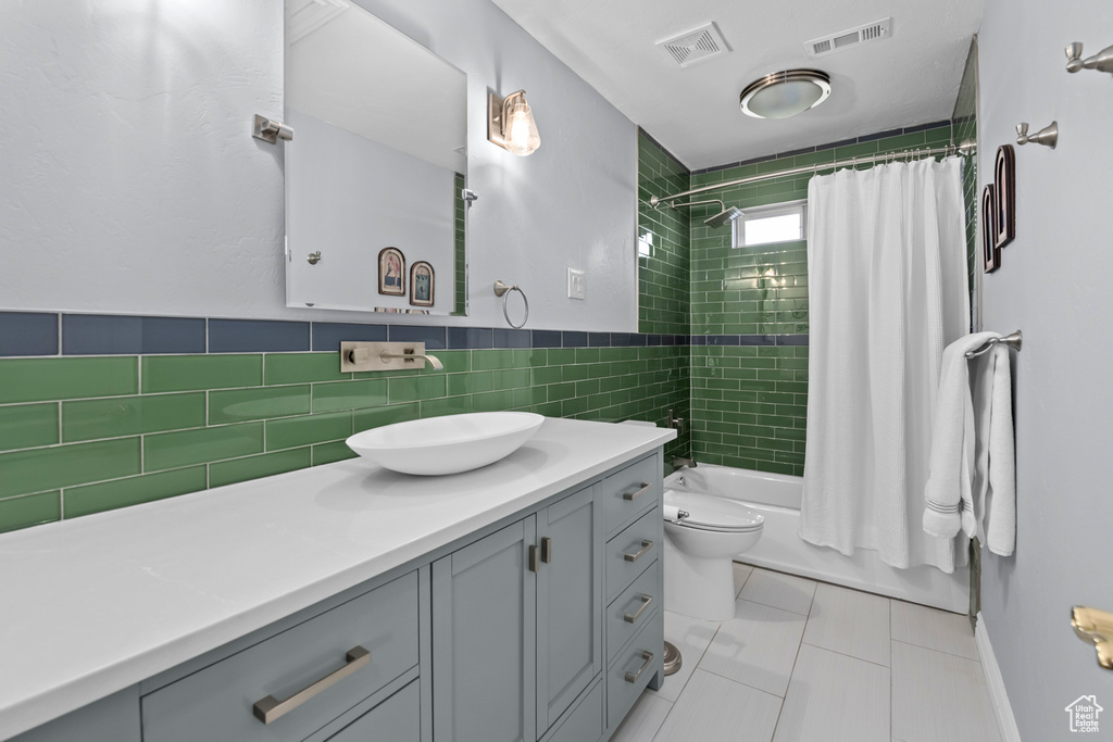 Full bathroom featuring tile walls, tile floors, shower / tub combo, toilet, and oversized vanity