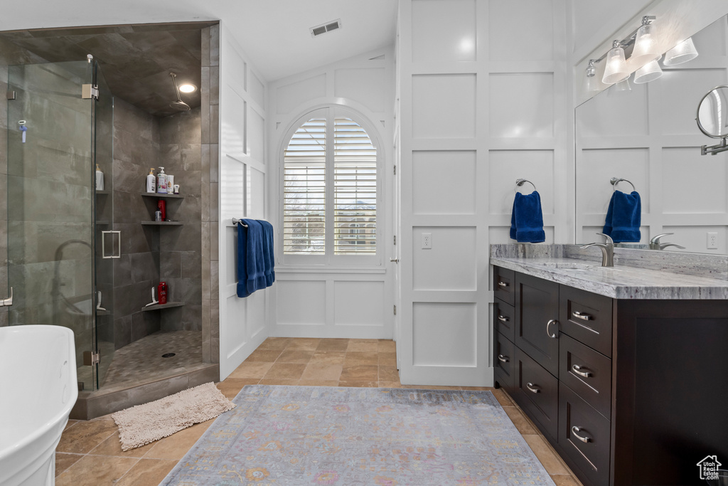 Bathroom with separate shower and tub, tile flooring, vanity, and vaulted ceiling