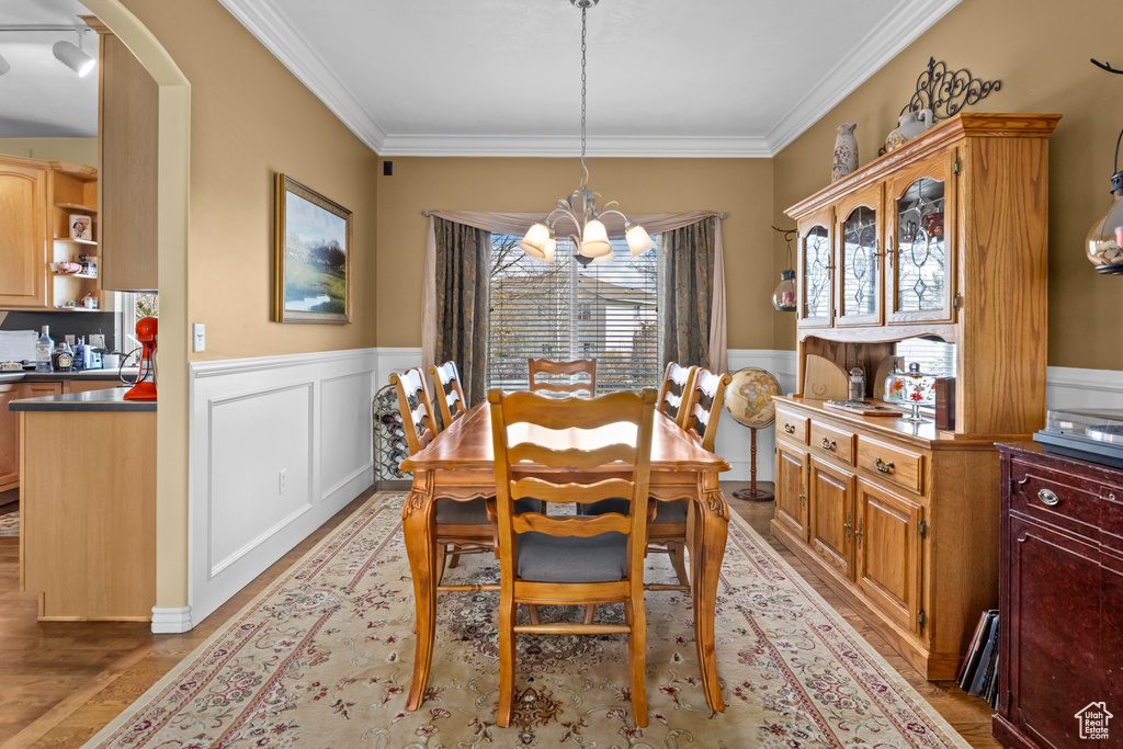 Dining room with crown molding, light hardwood / wood-style floors, and an inviting chandelier
