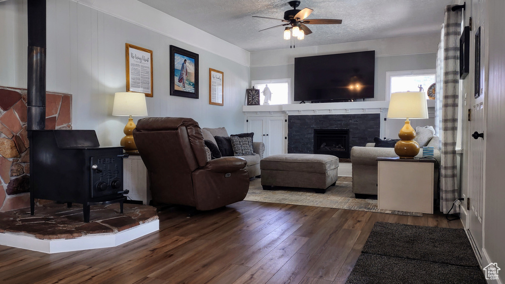 Living room featuring dark hardwood / wood-style flooring, ceiling fan, a wealth of natural light, and a textured ceiling