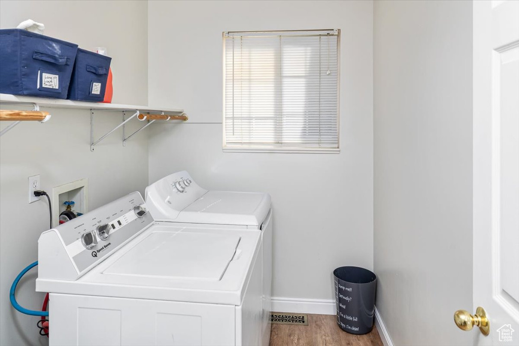 Clothes washing area with light hardwood / wood-style flooring, washing machine and dryer, and washer hookup