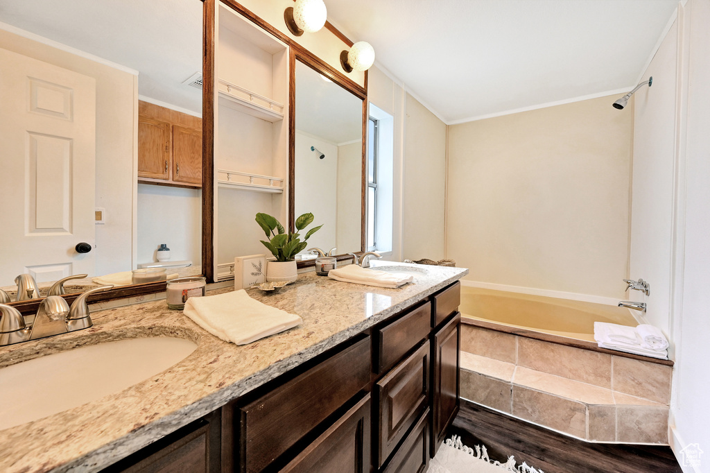 Bathroom with crown molding, hardwood / wood-style floors, double vanity, and  shower combination