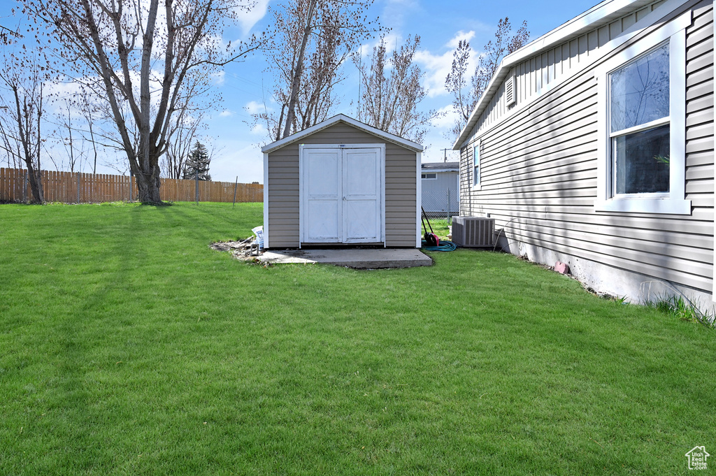 View of yard with central air condition unit and a shed