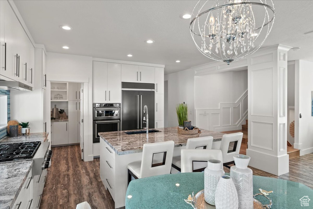 Kitchen featuring appliances with stainless steel finishes, dark hardwood / wood-style flooring, white cabinetry, and hanging light fixtures