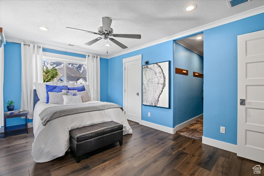 Bedroom with ceiling fan, ornamental molding, dark wood-type flooring, and a textured ceiling