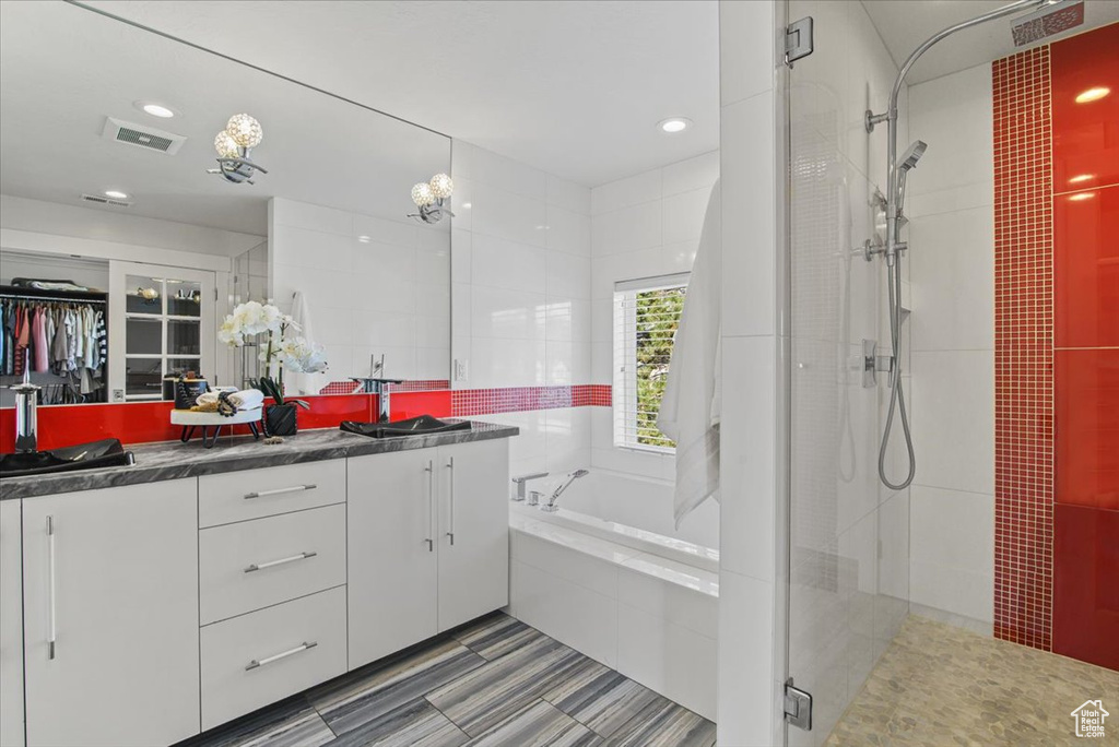 Bathroom featuring double vanity, tile floors, and shower with separate bathtub