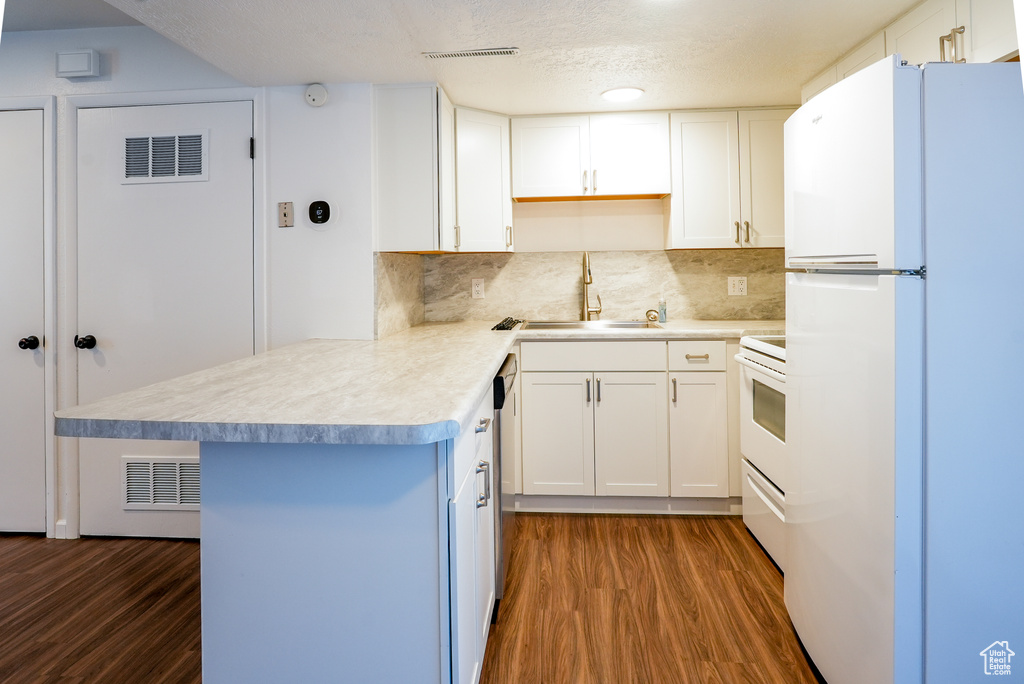 Kitchen featuring white cabinetry, dark hardwood / wood-style flooring, tasteful backsplash, and white appliances