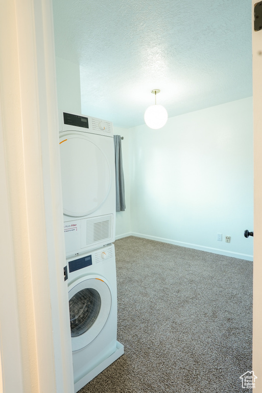 Laundry area featuring dark carpet and stacked washer / drying machine