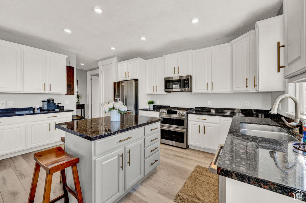 Kitchen with a center island, light hardwood / wood-style flooring, white cabinetry, stainless steel appliances, and sink