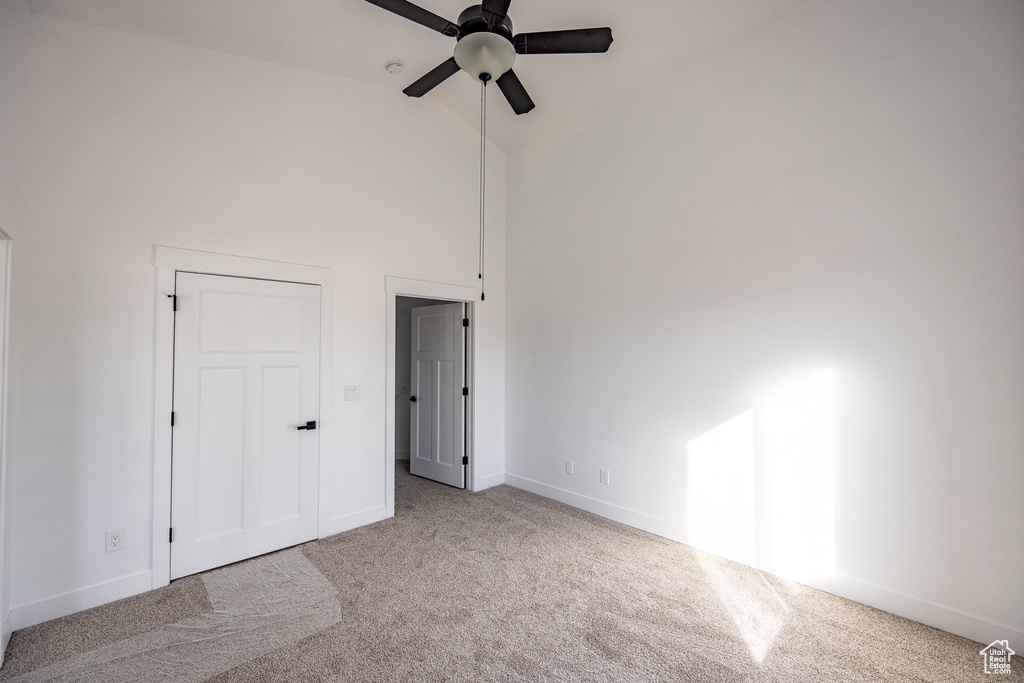 Unfurnished bedroom with light carpet, high vaulted ceiling, and ceiling fan