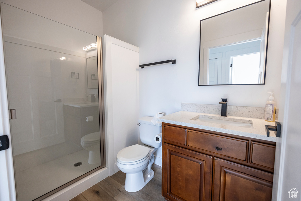 Bathroom featuring hardwood / wood-style flooring, toilet, vanity, and an enclosed shower