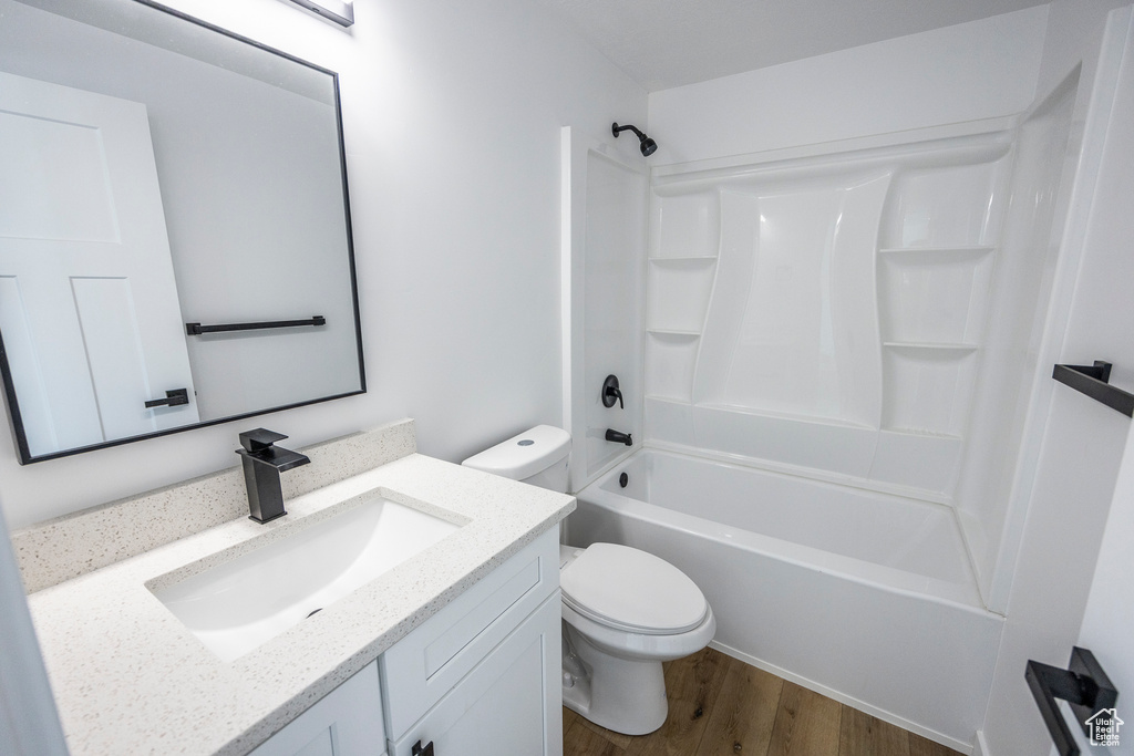Full bathroom with shower / bath combination, toilet, hardwood / wood-style floors, and vanity