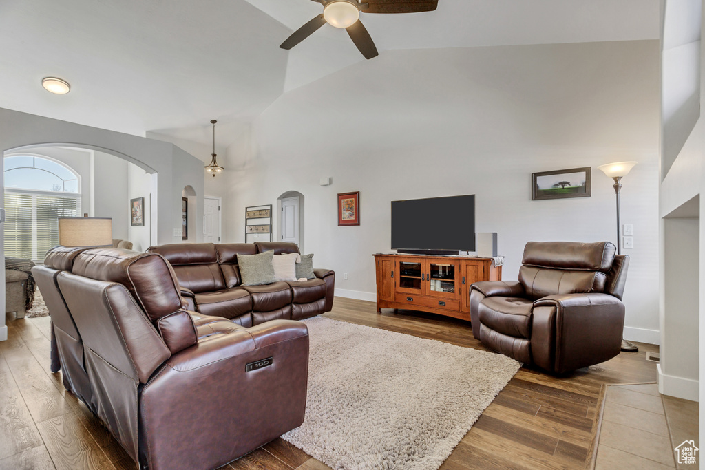Living room with high vaulted ceiling, ceiling fan, and hardwood / wood-style floors