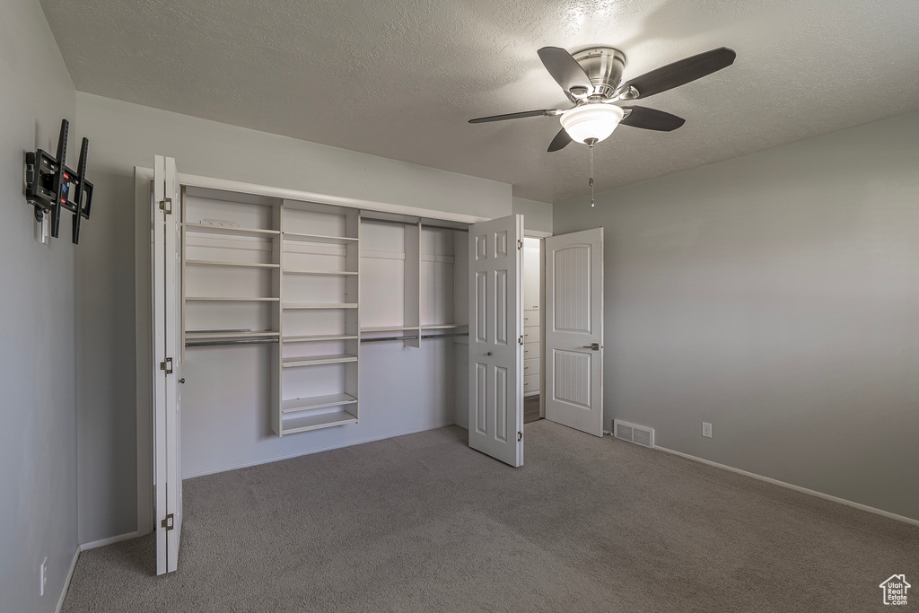 Unfurnished bedroom with ceiling fan, carpet flooring, a closet, and a textured ceiling
