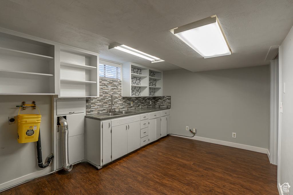 Kitchen featuring sink, dark hardwood / wood-style flooring, white cabinets, and tasteful backsplash