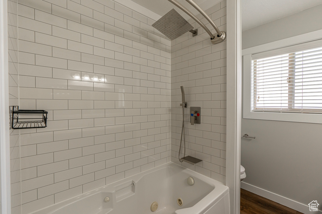 Bathroom featuring tiled shower / bath combo, toilet, and hardwood / wood-style flooring