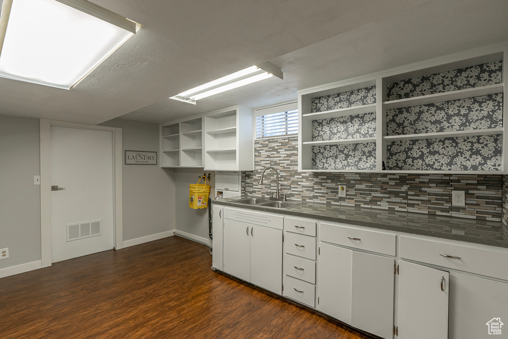 Kitchen featuring sink, dark wood-type flooring, white cabinets, and tasteful backsplash
