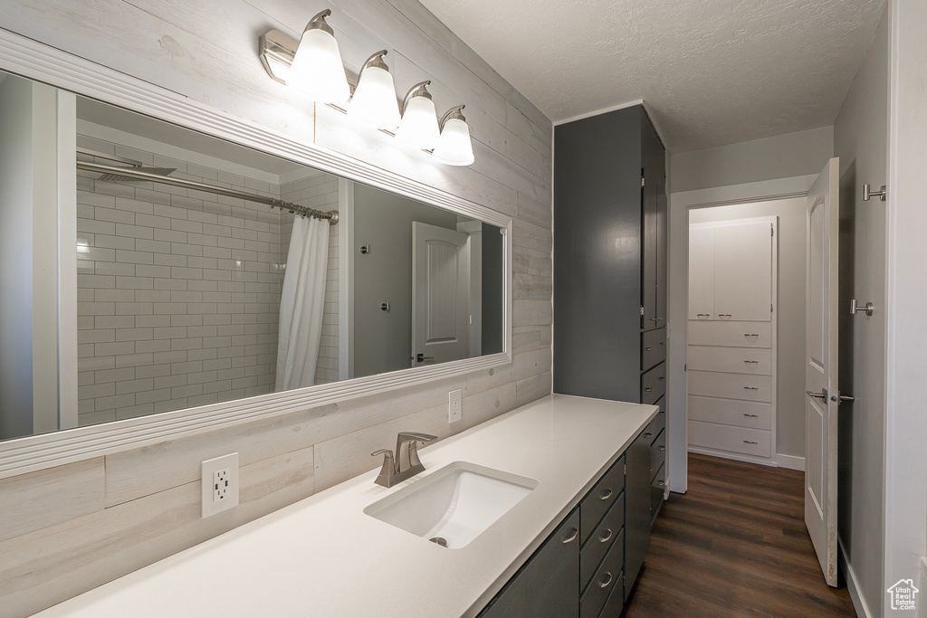 Bathroom with a textured ceiling, tile walls, hardwood / wood-style flooring, and vanity with extensive cabinet space