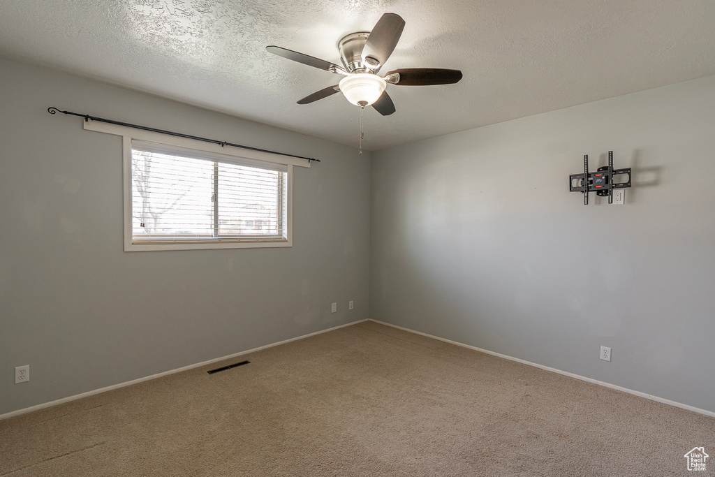 Unfurnished room with light colored carpet, a textured ceiling, and ceiling fan