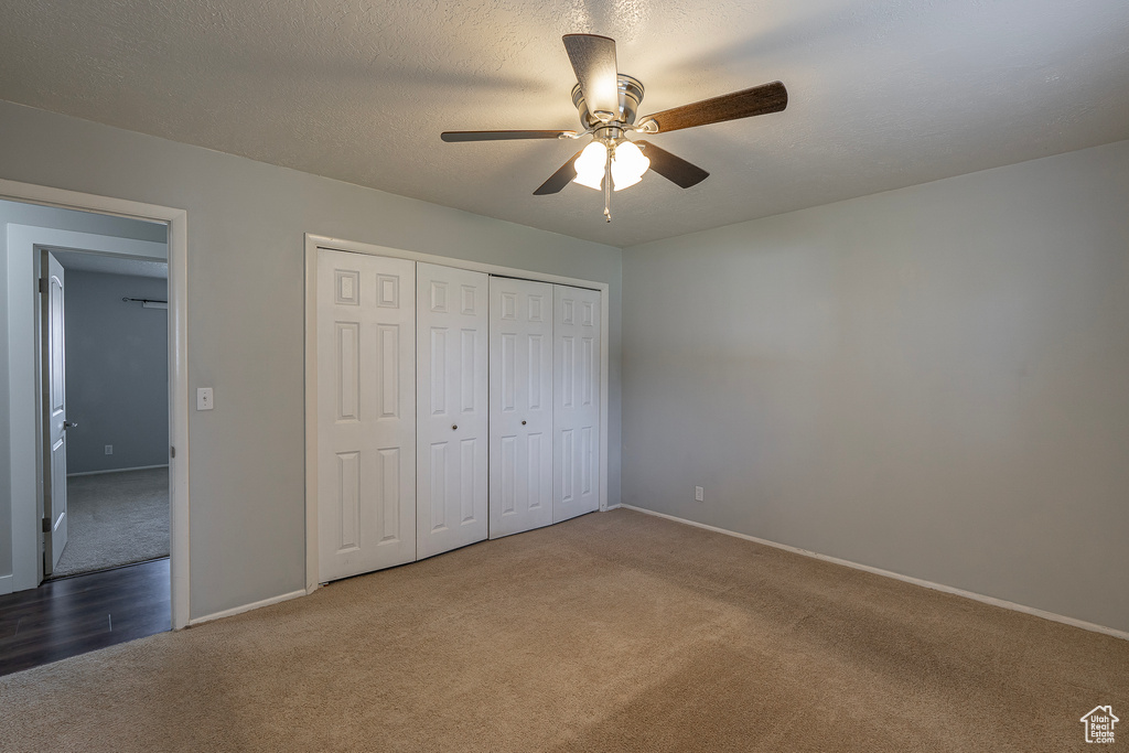 Unfurnished bedroom with a textured ceiling, a closet, ceiling fan, and light hardwood / wood-style flooring