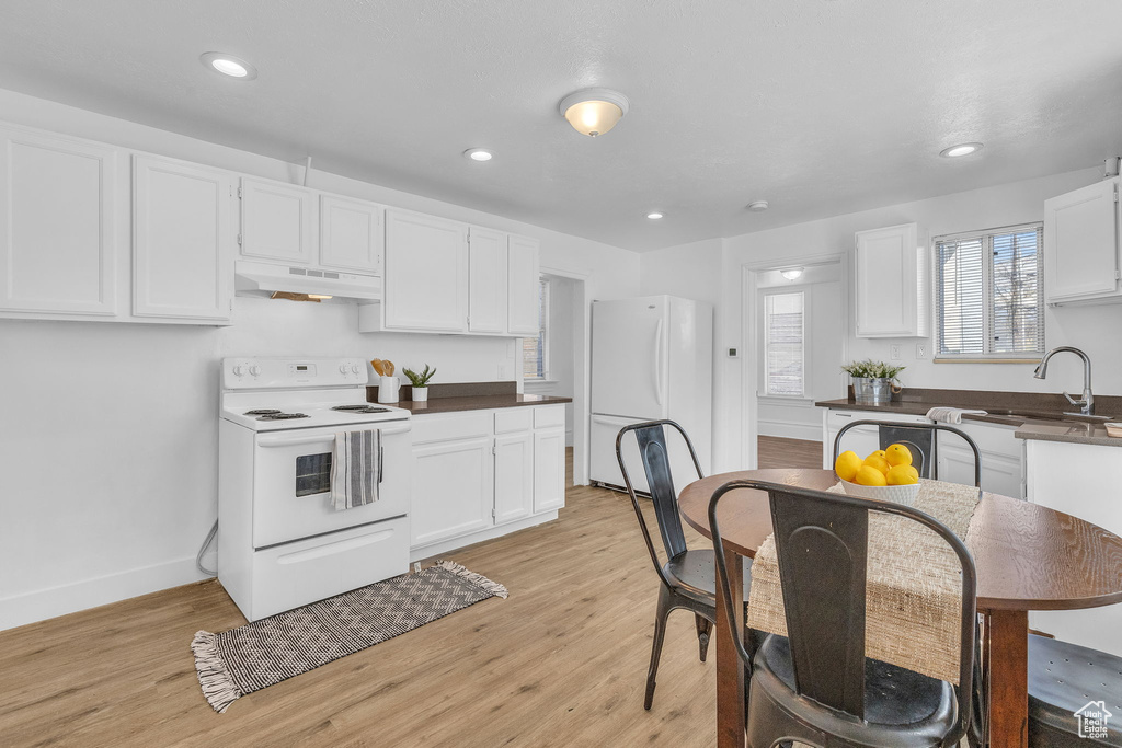 Kitchen with sink, light hardwood / wood-style floors, white cabinetry, and white appliances