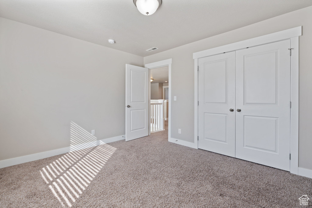 Unfurnished bedroom featuring light carpet and a closet